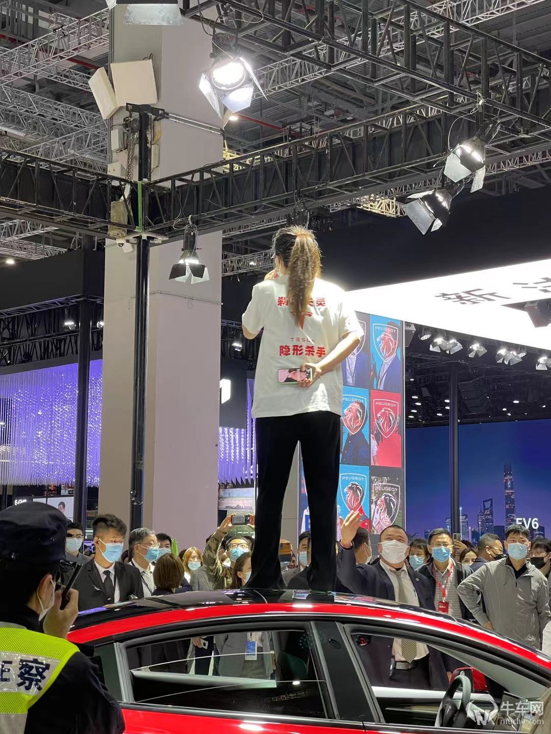 上海车展特斯拉展台女车主站在车顶维权遇工作人员暴力驱离